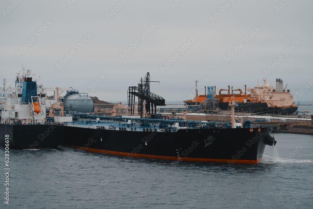 Floating storage and regasification unit. Liquified natural gas bunkering vessel and oil tanker powered by LNG in the port during the ship-to-ship operations.
