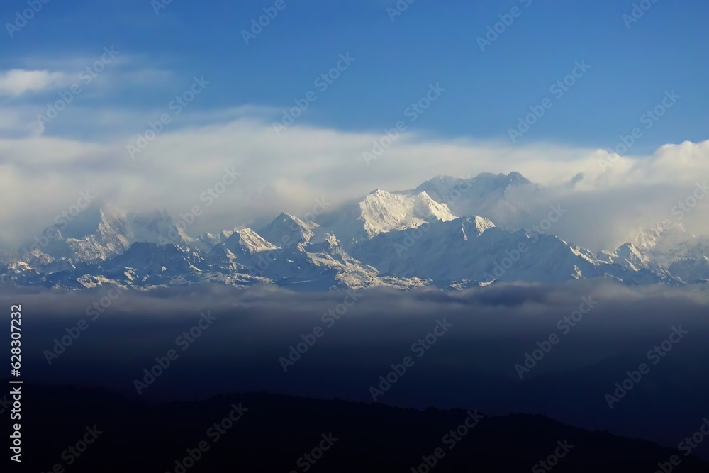 Behold the awe-inspiring beauty of Mt. Kanchenjunga, its majestic peak rising above the world, gracefully embraced by a sea of ethereal clouds, a breathtaking testament to nature's grandeur.