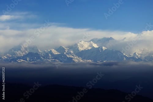 Behold the awe-inspiring beauty of Mt. Kanchenjunga, its majestic peak rising above the world, gracefully embraced by a sea of ethereal clouds, a breathtaking testament to nature's grandeur. © Tenzin & Li