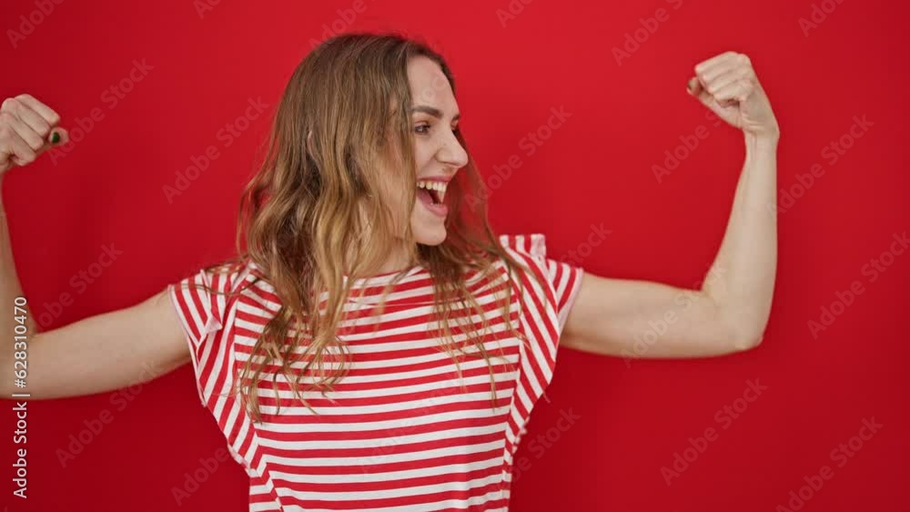 Young blonde woman smiling confident doing strong gesture with arms over isolated red background Young blonde woman smiling confident doing strong gesture with arms over isolated red background