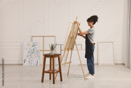 Young woman near wooden easel in studio