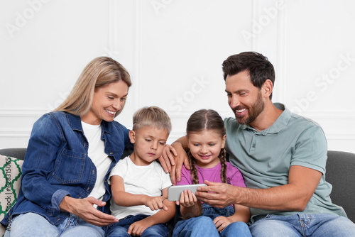 Happy family with smartphone spending time together on sofa at home