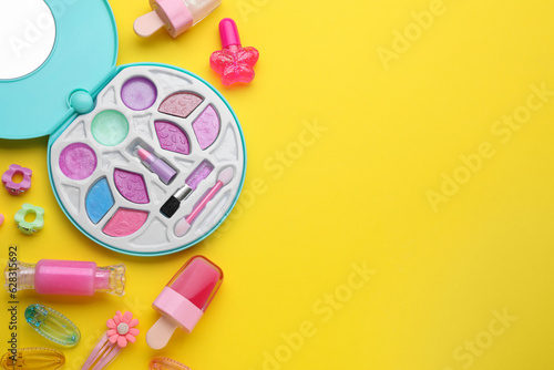 Eye shadow palette and other decorative cosmetics for kids on yellow background, flat lay. Space for text