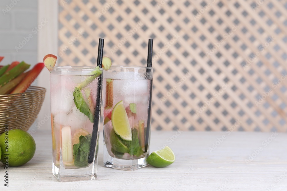 Fototapeta premium Tasty rhubarb cocktail with lime on white wooden table, space for text