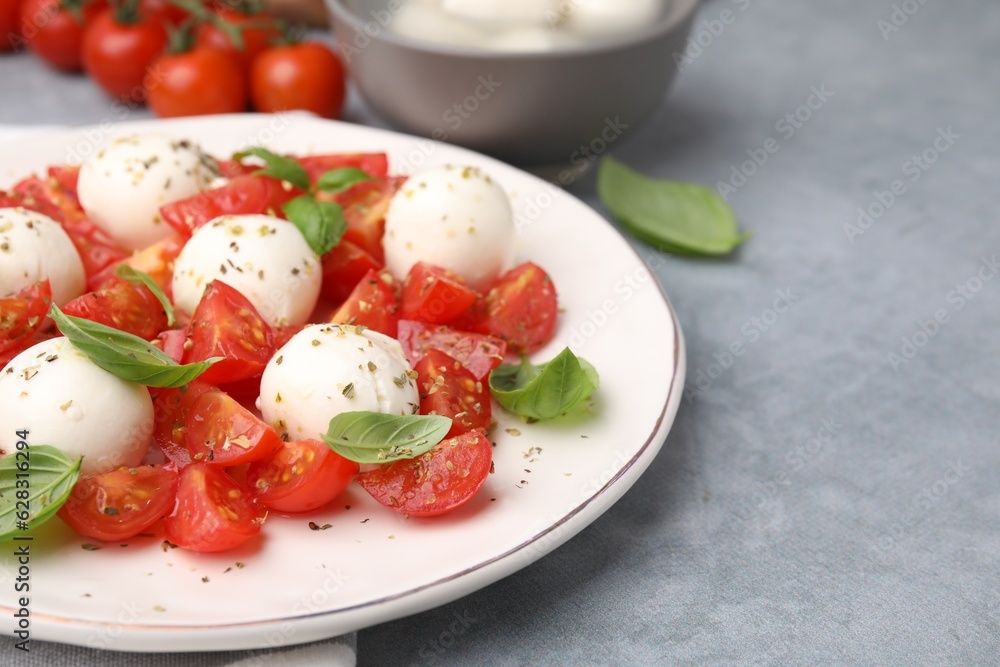 Tasty salad Caprese with tomatoes, mozzarella balls and basil on grey table, closeup. Space for text Tasty salad Caprese with tomatoes, mozzarella balls and basil on grey table, closeup. Space for text