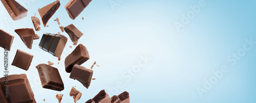 Broken chocolate bar pieces falling on light blue background. Banner design with space for text