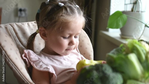 Little girl eats fresh pear. Healthy food. Vitamins and healthy raw fruct from an early age for babies. Proper nutrition photo