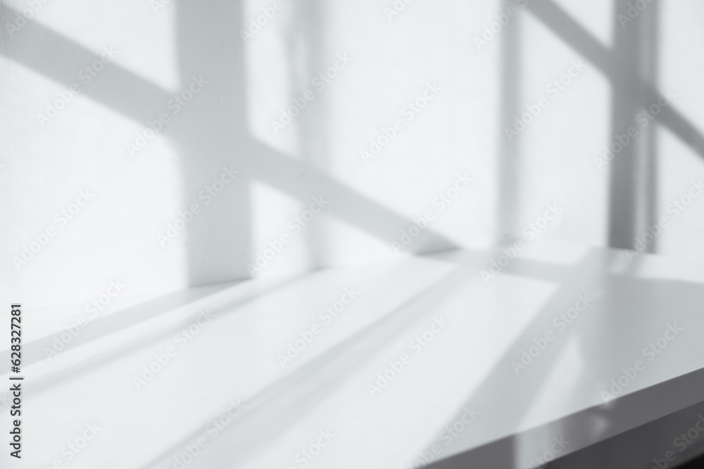 Obraz premium Empty tabletop with window shadow on concrete wall texture background, suitable for product presentation backdrop.