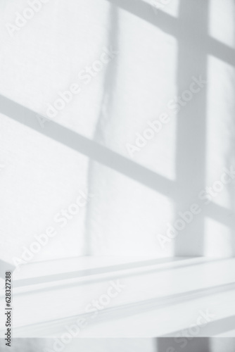 Empty tabletop with window shadow on concrete wall texture background, suitable for product presentation backdrop.