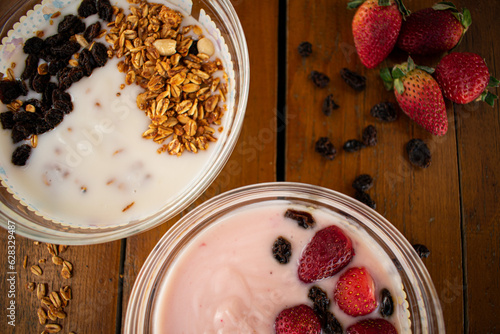 Yogurt natural y de fresa con cereales fresas y pasas sobre una mesa de madera en una toma zenital  photo