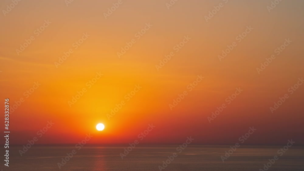 Time-lapse sunrise over beautiful hills or mountains horizon, dawn warm morning sunlight reflected on calm sea water surface. Bright hue orange sun rises behind mountain range silhouette skyline Time-lapse sunrise over beautiful hills or mountains horizon, dawn warm morning sunlight reflected on calm sea water surface. Bright hue orange sun rises behind mountain range silhouette skyline