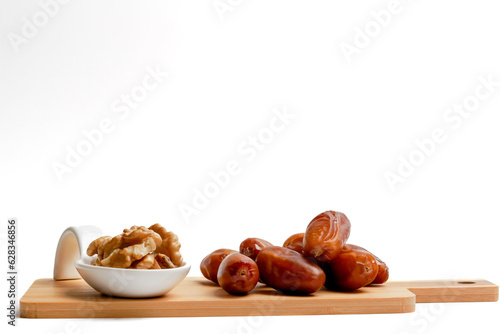 fresh dates with walnuts on a wooden board with a white background