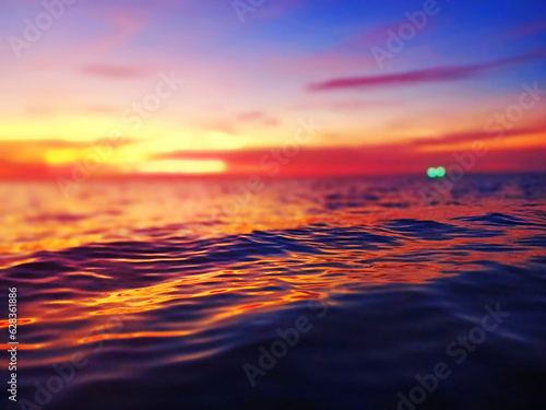 Sea sunset soft blurred background, ocean sunrise, tropical island beach dawn, dark blue water waves splash, ripple texture, colorful red pink purple yellow clouds sky, sun reflection, evening, night © Vera NewSib