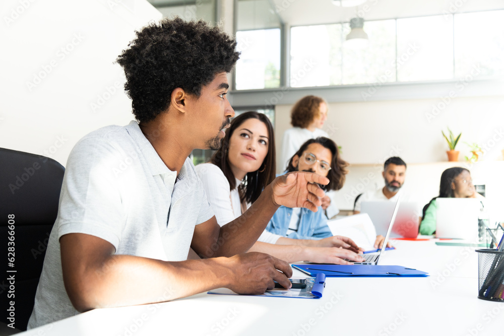 Young african american man talking to coworkers about business in conference room table. Copy space. Young african american man talking to coworkers about business in conference room table. Copy space.