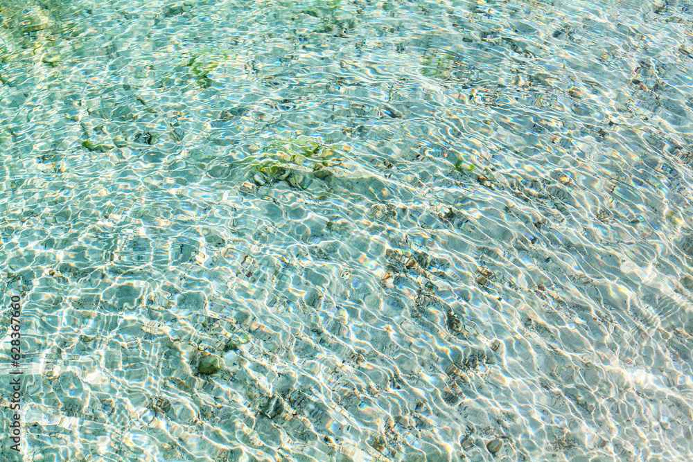Sea water round waves texture, ripples water surface, concentric rings of falling drops, transparent light blue ocean water top view, clear aqua background, sun glow reflection, tropical island beach Sea water round waves texture, ripples water surface, concentric rings of falling drops, transparent light blue ocean water top view, clear aqua background, sun glow reflection, tropical island beach