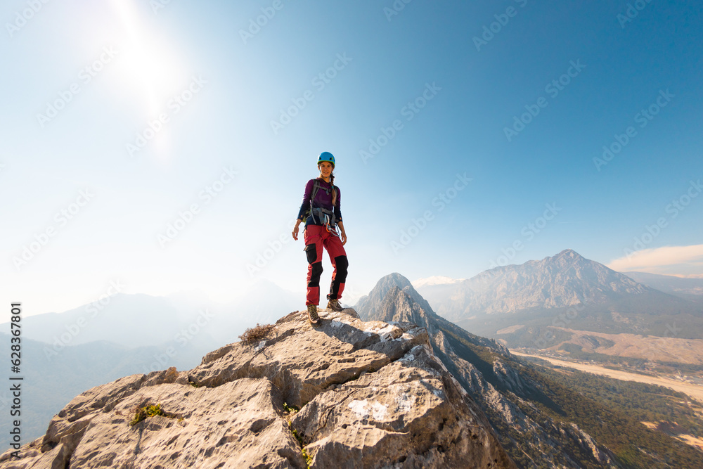 young girl climber in a helmet and with a backpack walks along a mountain range against the backdrop of mountains and climbing and hiking.