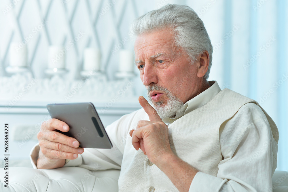 thoughtful senior man using tablet at home thoughtful senior man using tablet at home