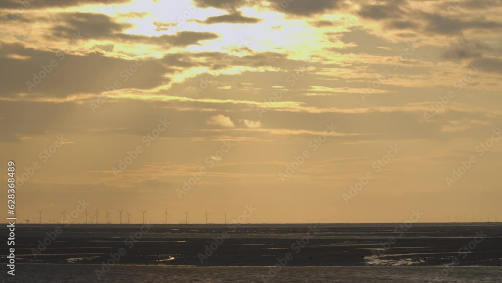 Setting sun rays moving across horizon with distant windmills spinning. Time lapse 30x. Sony FX30. Setting sun rays moving across horizon with distant windmills spinning. Time lapse 30x. Sony FX30.