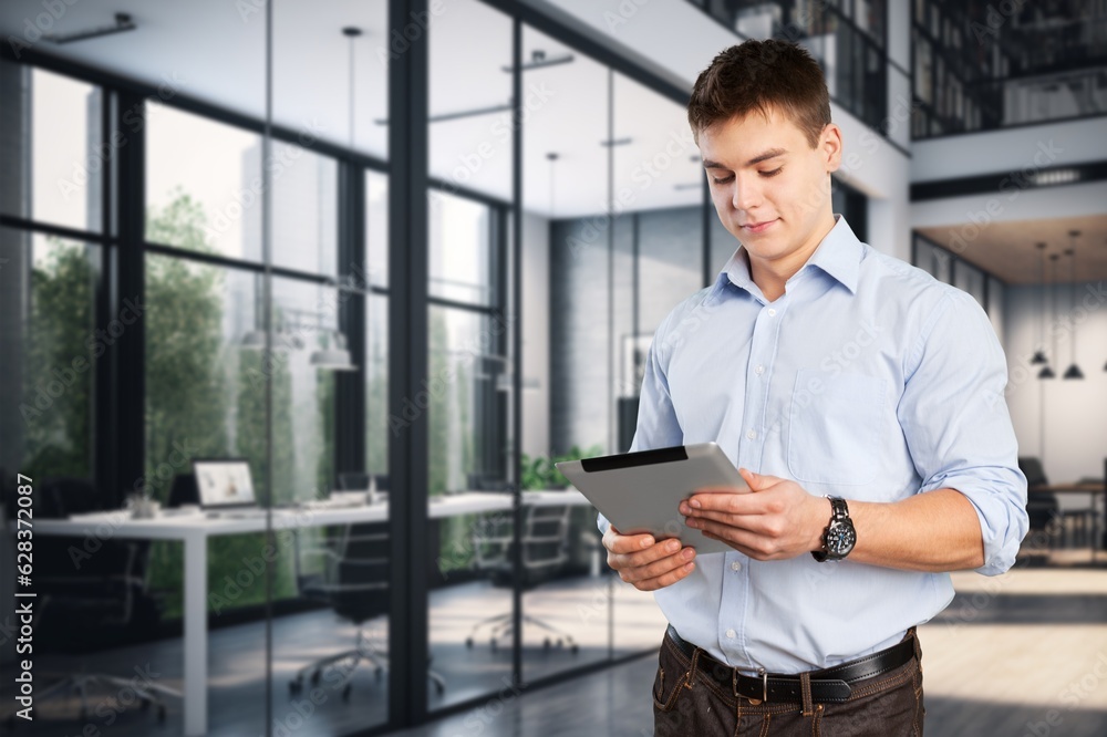 Handsome young businessman works on digital tablet in the office Handsome young businessman works on digital tablet in the office
