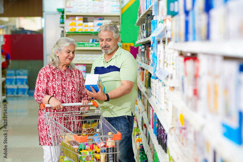 Senior indian couple purchasing together at grocery shop.