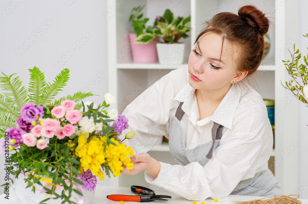 A florist girl holding a bouquet in her hands in a florist shop A florist girl holding a bouquet in her hands in a florist shop