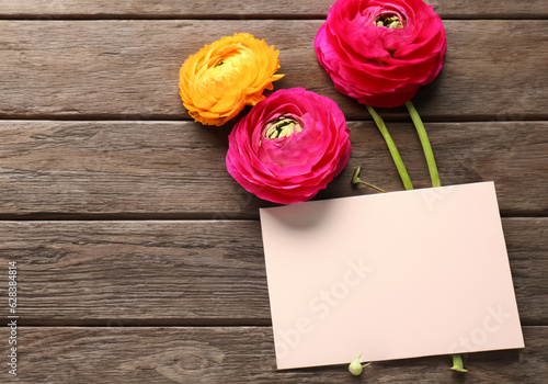 Beautiful ranunculus flowers and card on wooden background MADE OF AI