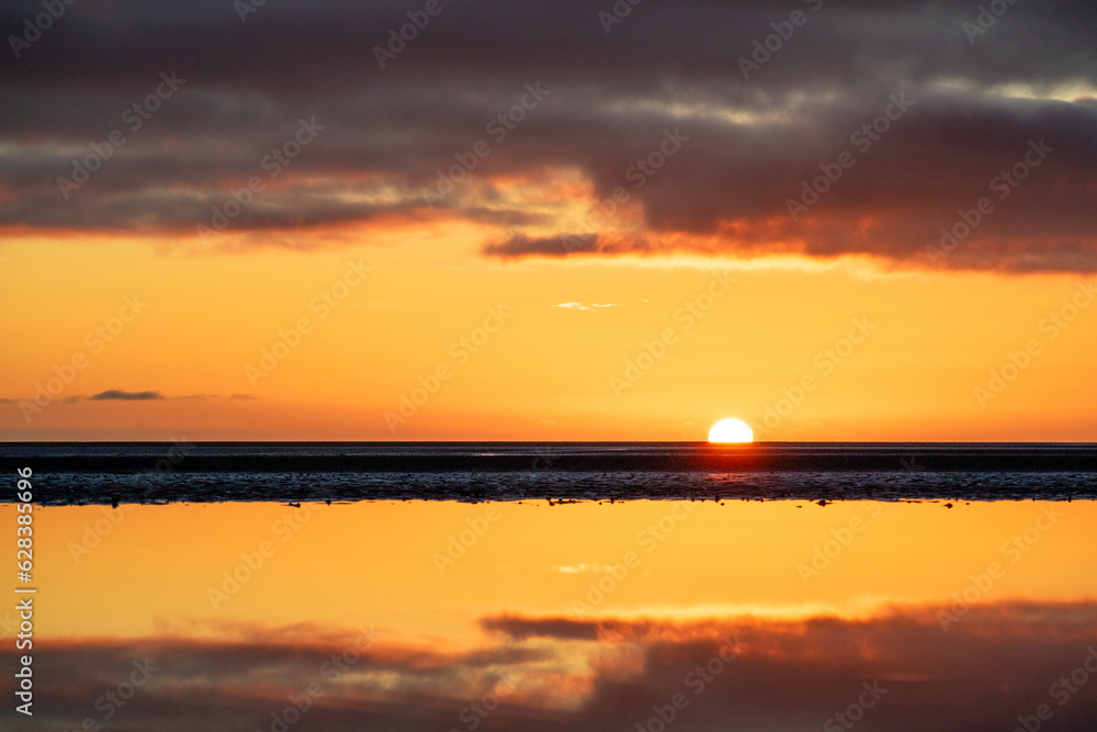Golden sunrise with reflection and dramatic clouds