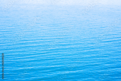 Abstract photo of Sun light reflecting or sparkling glitter on water of sea or ocean with beautiful sky blue light tone.