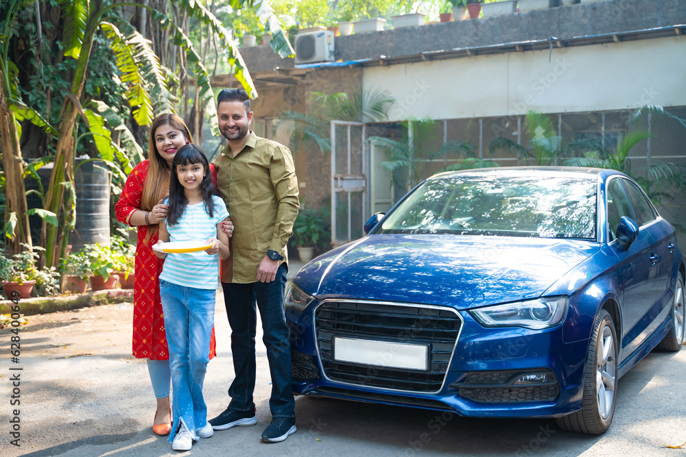 Indian family standing with new car. girl holding puja thali in hand. Indian family standing with new car. girl holding puja thali in hand.