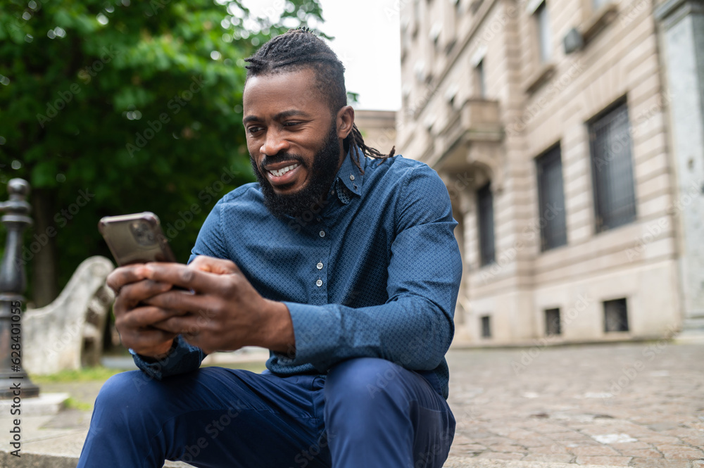 Dark-skinned young man in denim clothes with a phone in hand Dark-skinned young man in denim clothes with a phone in hand