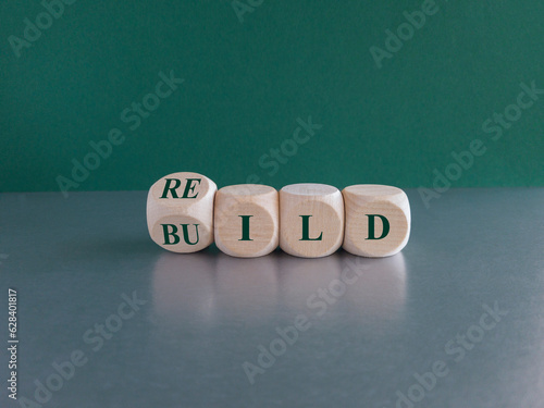 Rebuild symbol. Concept green word rebuild on wooden cubes on a beautiful grey table. Green background. Business and rebuild concept. Copy space.