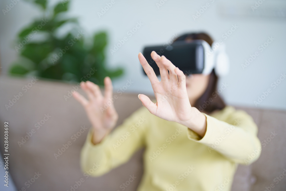 Young Asian woman gamer wearing virtual reality touching air during the VR experience Future home technology player hobby playful enjoyment concept. Young Asian woman gamer wearing virtual reality touching air during the VR experience Future home technology player hobby playful enjoyment concept.