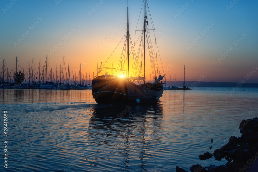 Yacht marina on the Balaton lake at sunset, scenic view of the boats, sun, blue sky and water with reflection, outdoor travel background, Siofok, Hungary