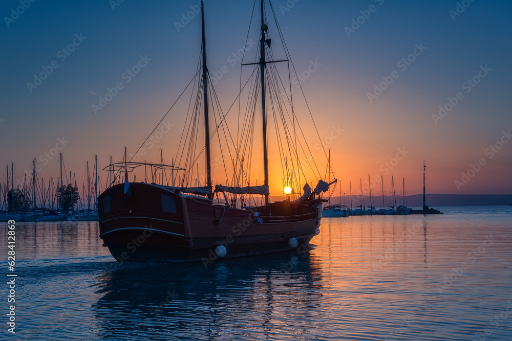 Yacht marina on the Balaton lake at sunset, scenic view of the boats, sun, blue sky and water with reflection, outdoor travel background, Siofok, Hungary