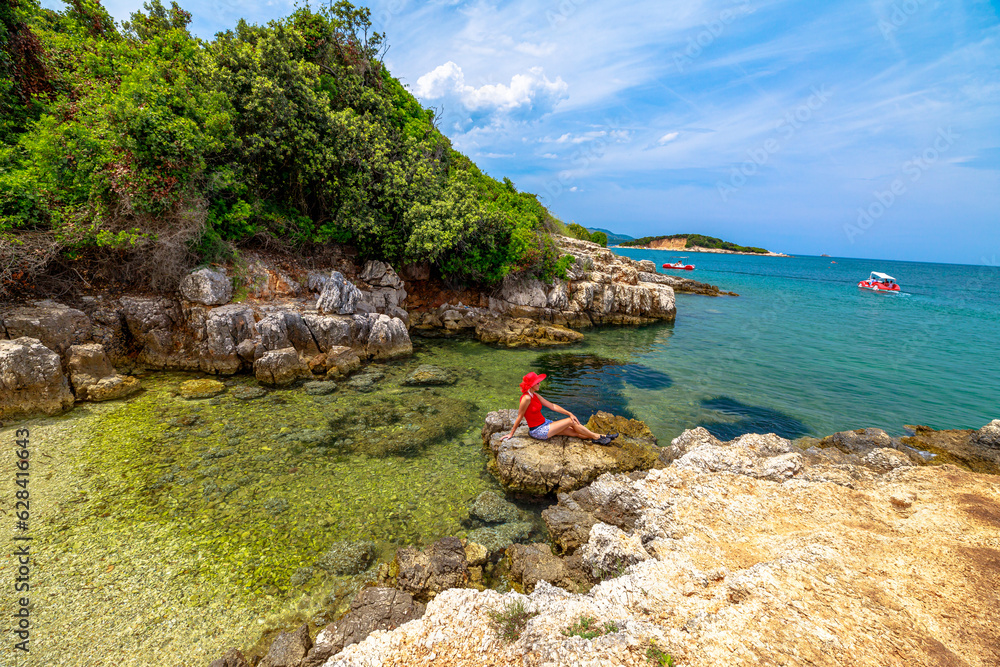 woman sunbathing on the sandy shores of Ishul Ksamil Island from a top perspective. People are disembarking to explore the beautiful beach in the Ksamil archipelago of Albania.