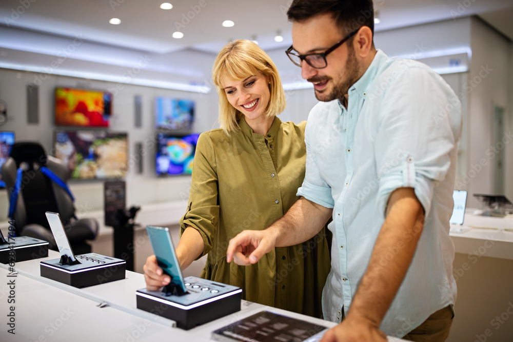 Shopping a new digital device. Happy couple buying a smartphone in store. Shopping a new digital device. Happy couple buying a smartphone in store.