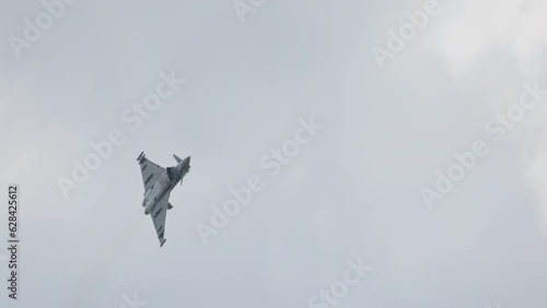 Fast fighter jet during high speed combat maneuvers with clouds photo