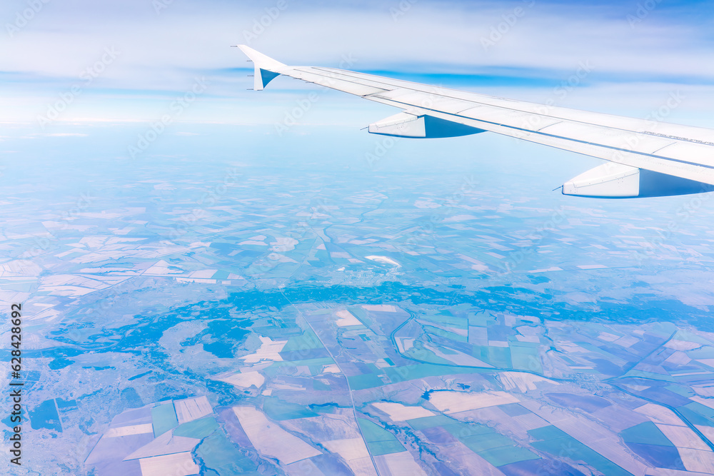 Aerial view from airplane window above green ground. View from the airplane window with beautiful clouds at sunrise Aerial view from airplane window above green ground. View from the airplane window with beautiful clouds at sunrise