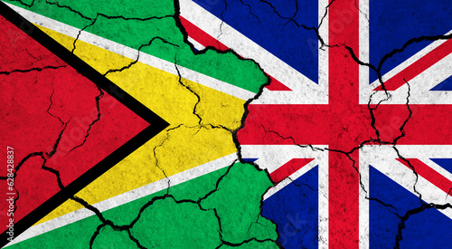 Flags of Guyana and United Kingdom on cracked surface - politics, relationship concept