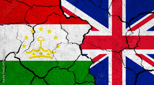 Flags of Tajikistan and United Kingdom on cracked surface - politics, relationship concept