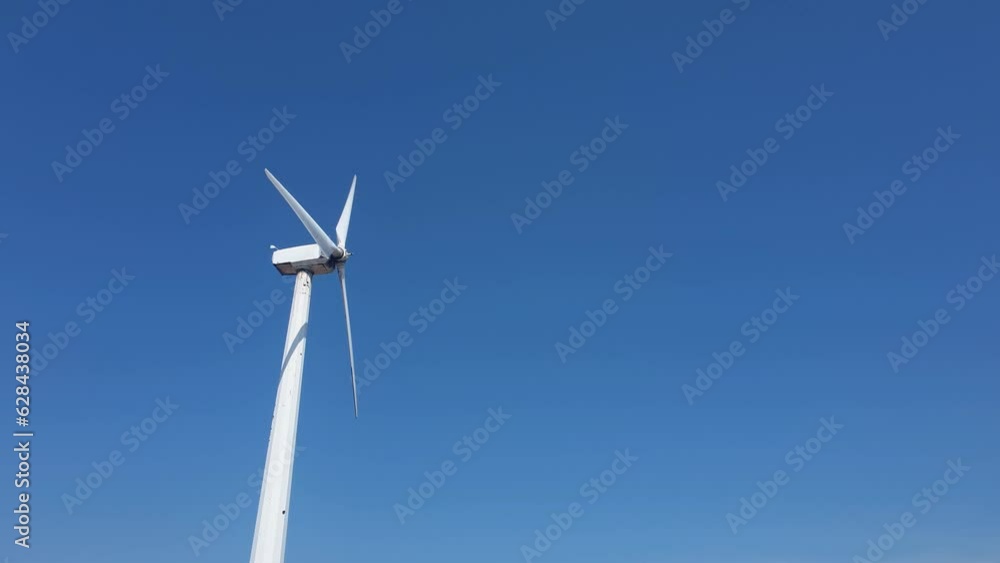 The rotor of a wind turbine rotates rapidly against the blue sky. Static shot taken on a sunny day. The rotor of a wind turbine rotates rapidly against the blue sky. Static shot taken on a sunny day.