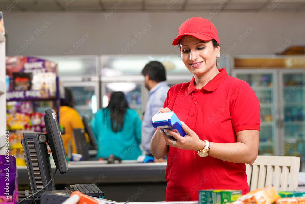 Indian female cashier using swipe machine at supermarket. digital payment concept. Indian female cashier using swipe machine at supermarket. digital payment concept.