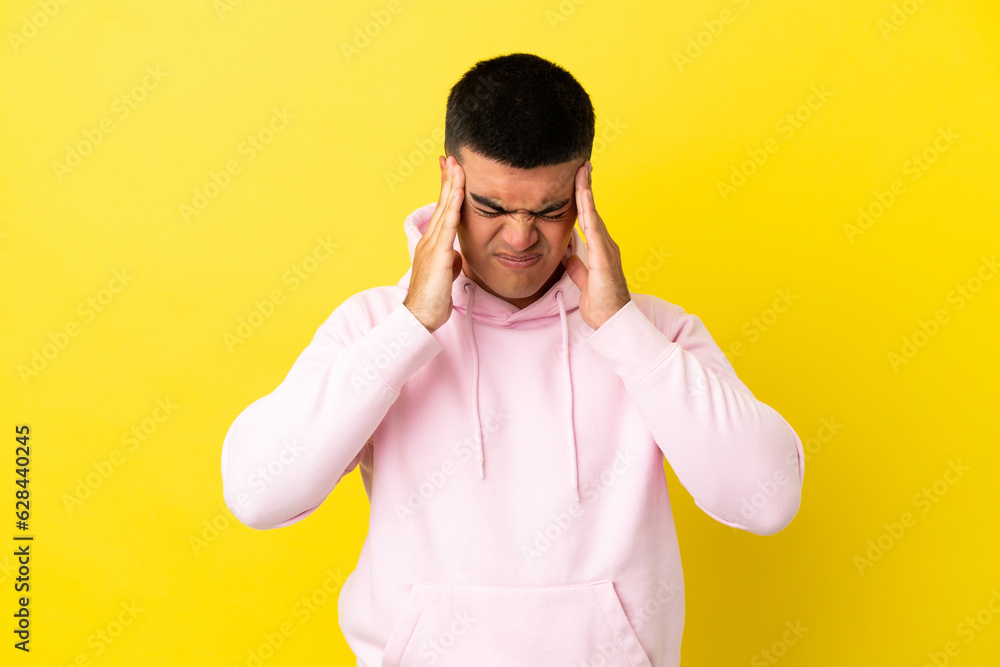 Young handsome man over isolated yellow background with headache Young handsome man over isolated yellow background with headache