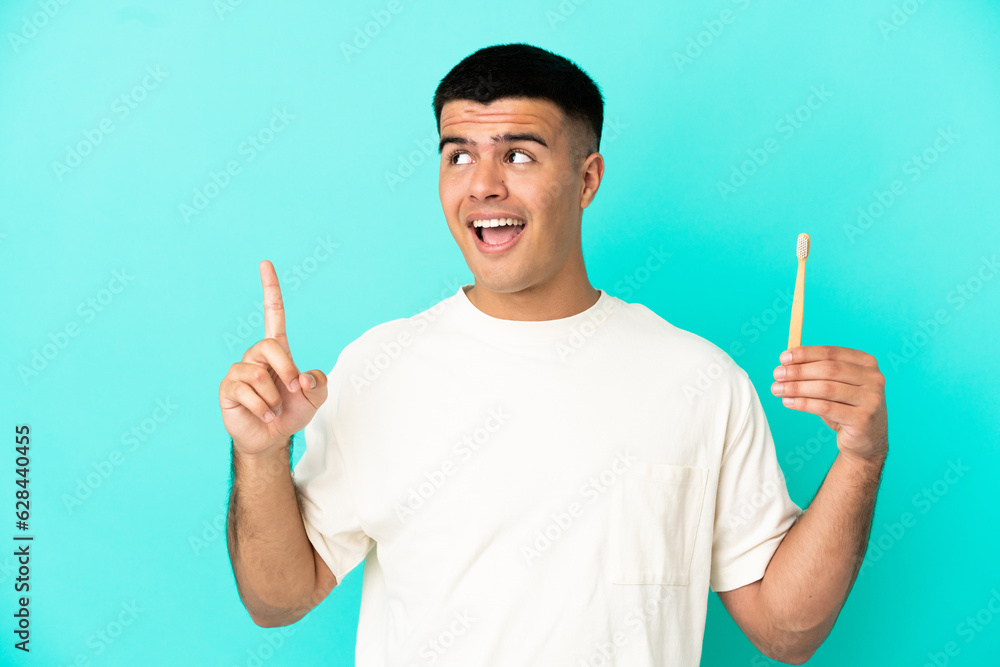 Young handsome man brushing teeth over isolated blue background pointing up a great idea Young handsome man brushing teeth over isolated blue background pointing up a great idea