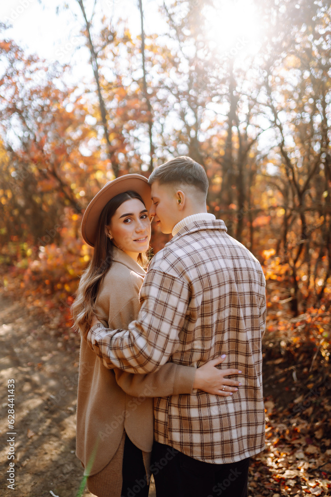 Happy and young couple walks in a beautiful autumn park, enjoys the beautiful weather. Pregnant married couple resting together in nature. Vacation, lifestyle concept. Happy and young couple walks in a beautiful autumn park, enjoys the beautiful weather. Pregnant married couple resting together in nature. Vacation, lifestyle concept.