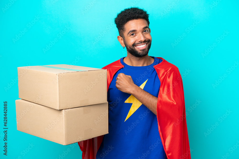 Obraz na plátně Super Hero delivery Brazilian man isolated on blue background celebrating a vict