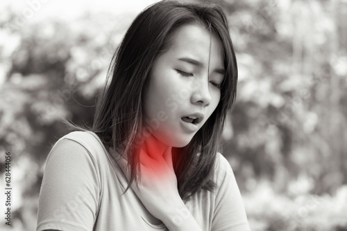 sick asian woman having sore throat; concept of sickness with coughing, hiccupping, choking, acid reflux photo