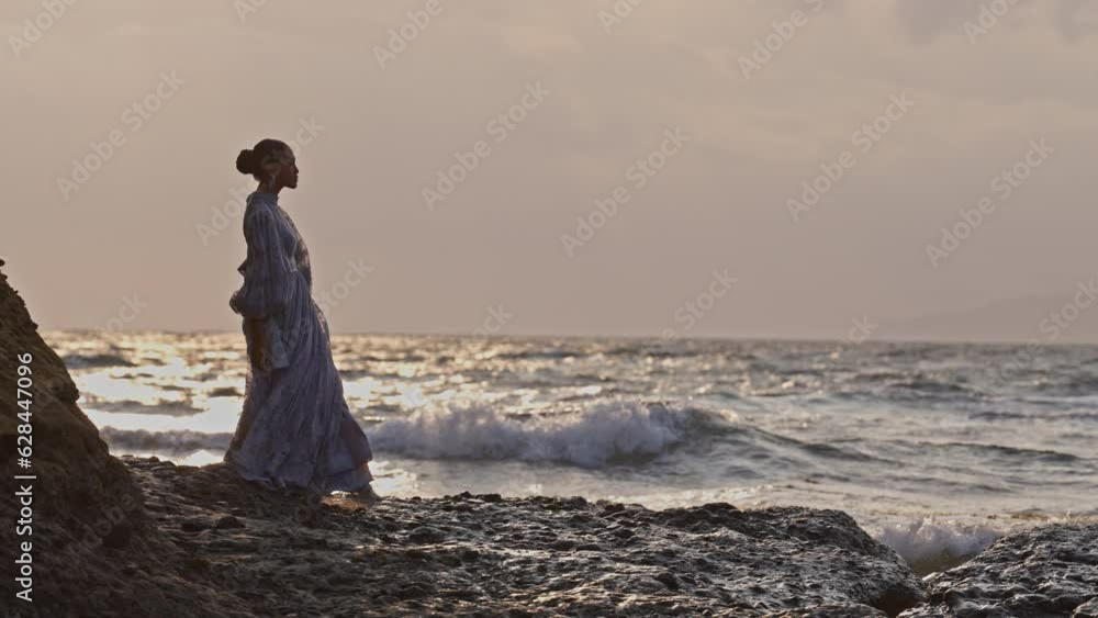Woman In A Dress Walks At Rocky Seashore Woman In A Dress Walks At Rocky Seashore