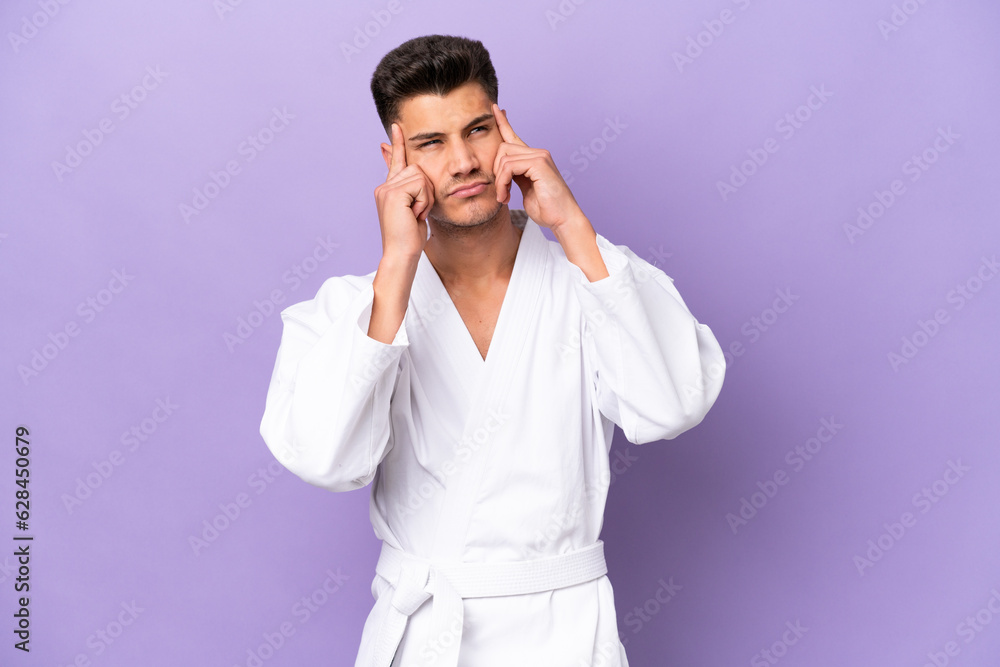 Young caucasian man doing karate isolated on purple background having doubts and thinking Young caucasian man doing karate isolated on purple background having doubts and thinking