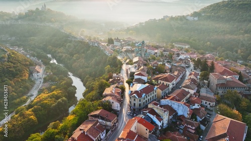 Aerial shot of sunny slightly foggy morning in Veliko Tarnovo, Bulgaria. Flying over old houses, Ascension Cathedral and river in the canyon in Veliko Tarnovo 2 photo